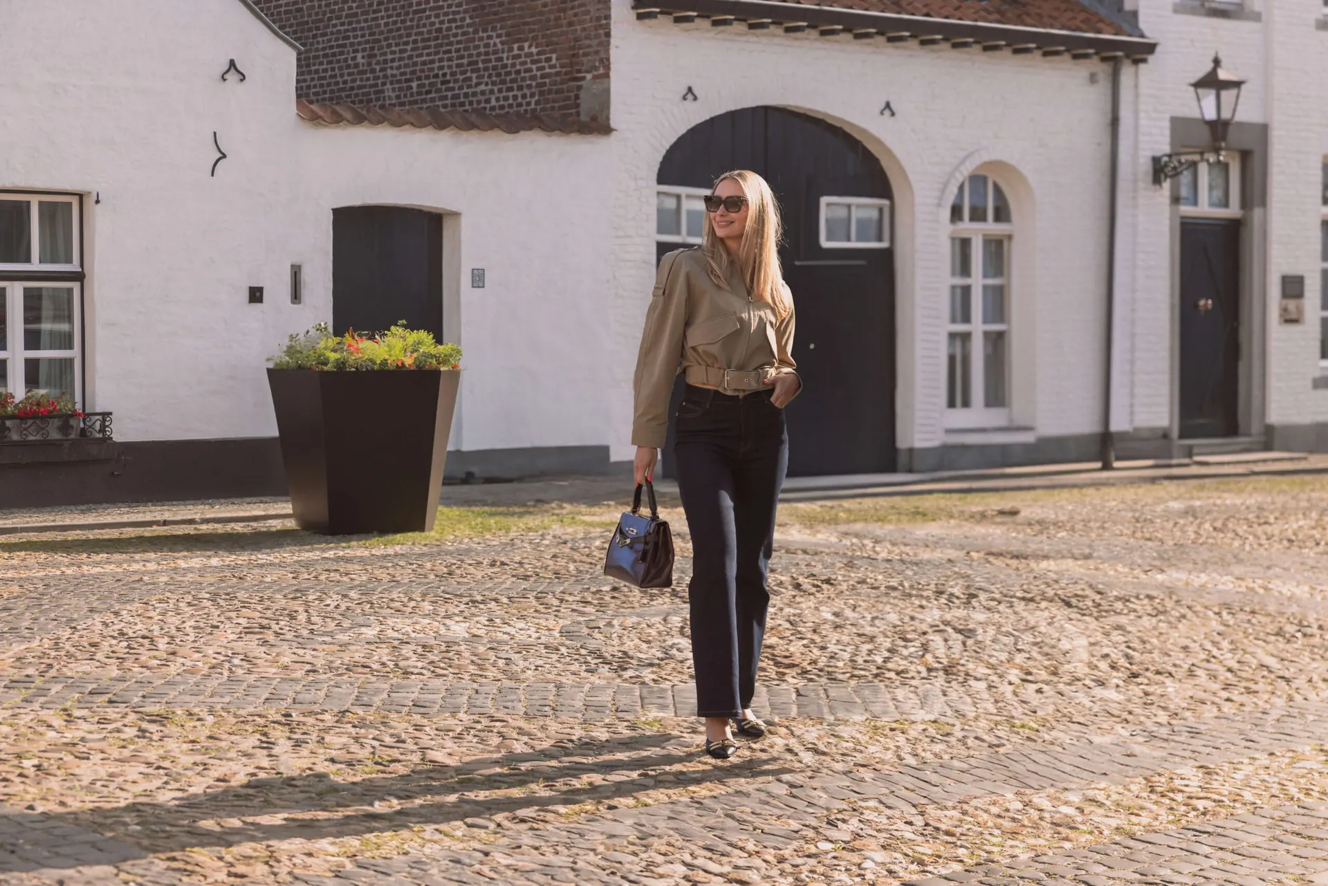 Model in de Petite Retro Flared Jeans in Dark Blue op een kasseienplein in Limburg